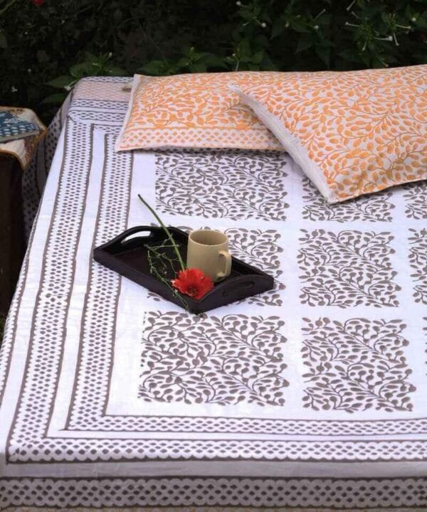 Brown and white king size bed sheet with two reversible tan pillow covers adorned on a double bed in the middle of a green meadow to enhance slow morning tea.