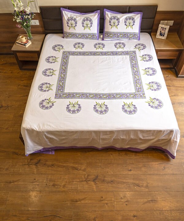 A luxurious king size double bed draped in kalaaai's organic cotton bed sheet in white and purple colors hand block printed in minimalistic floral design