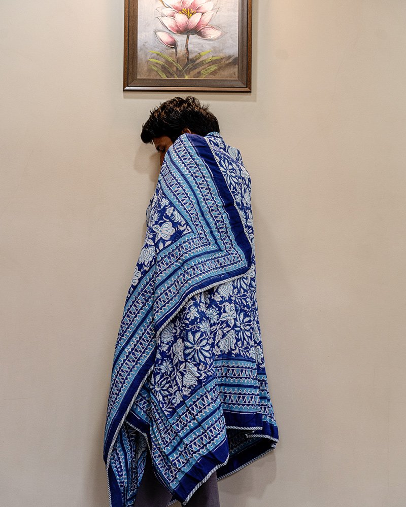 Indigo blue and white reversible organic cotton dohar is wrapped by a man for a cozy lone time in his beautiful home