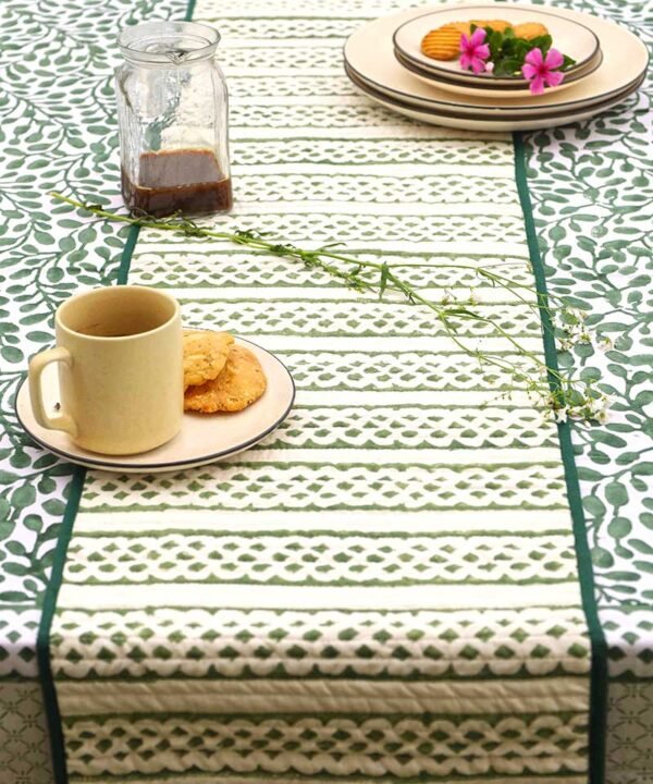 Kalaaai Organic cotton reversible heat proof green and white table runner set on a dining table with green and white table cloth for morning coffee with coffee mug, cookies, coffee and lots of freshness for a great start to the day.