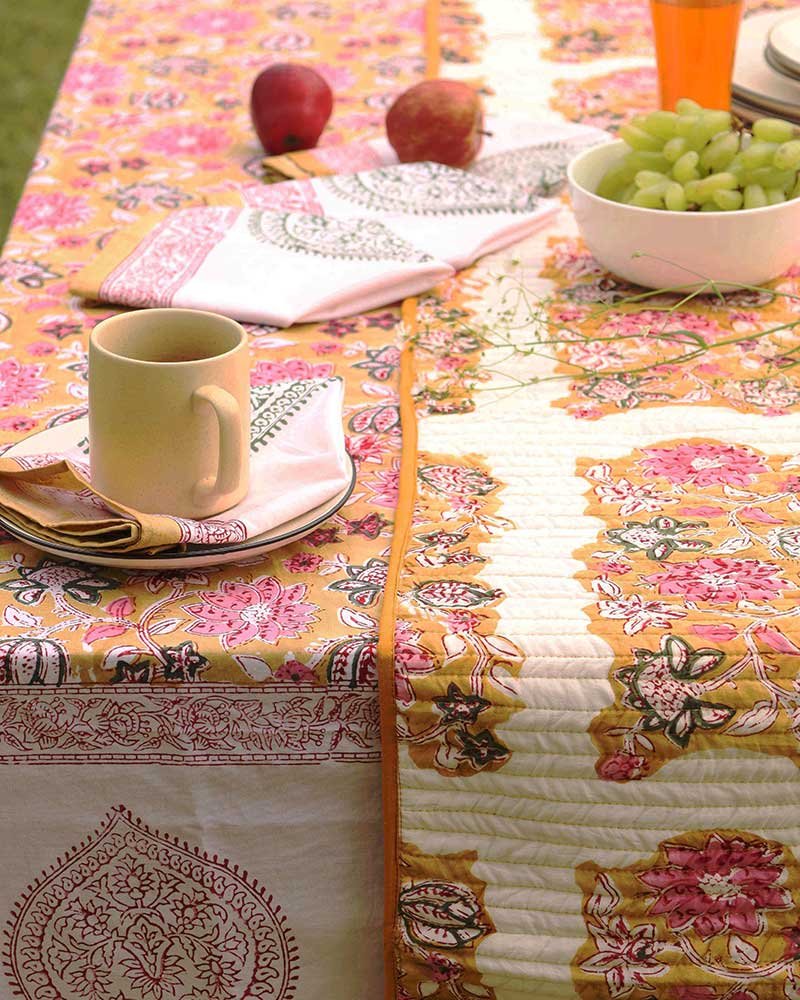 Kalaaai hand crafted organic cotton contemporary table runner in reversible floral design set on a dining table showing Ochre side with beautiful floral design in ochre and pink colors. this is set on a coordinating ochre tale cloth with coordinating napkins for a special healthy breakfast.