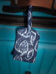 UPCYCLE ALERT: Meet the Zero-Waste Luggage Tag. Cluster of vibrant, unique Upcycled Fabric Story Tags. Launch banner emphasizing conscious travel and 1-by-1 artisan craftsmanship.