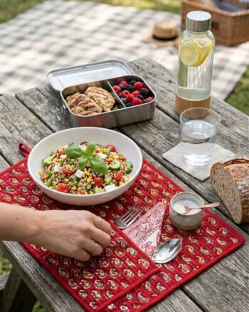 Hand block printed Paisley Roll-Up Travel Mat set by Kalaaai featuring a deep red quilted cotton mat with yellow paisley motifs, integrated cutlery pocket, reusable spoon, fork, and napkin. A heritage-inspired, eco-friendly lifestyle accessory designed for sustainable dining on the go.