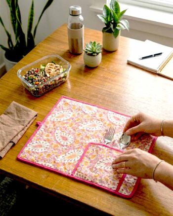 Kalaaai Paisley Roll-Up Travel Mat in pink hand block print, handcrafted quilted cotton dining mat with cutlery pocket, inspired by Indian heritage textiles and sustainable living being used in office for lunch